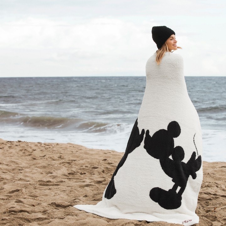 a model wrapped in a white blanket with a silhouette of mickey and minnie kissing on it