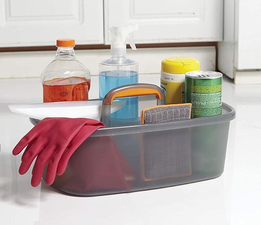 bottles of cleaning products and a sponge and glove in the caddy