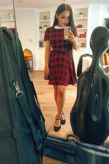A reviewer wearing the above the knee dress in red plaid