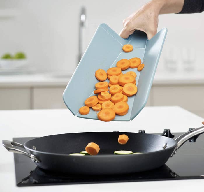 Foldable cutting board transporting veggies to pan