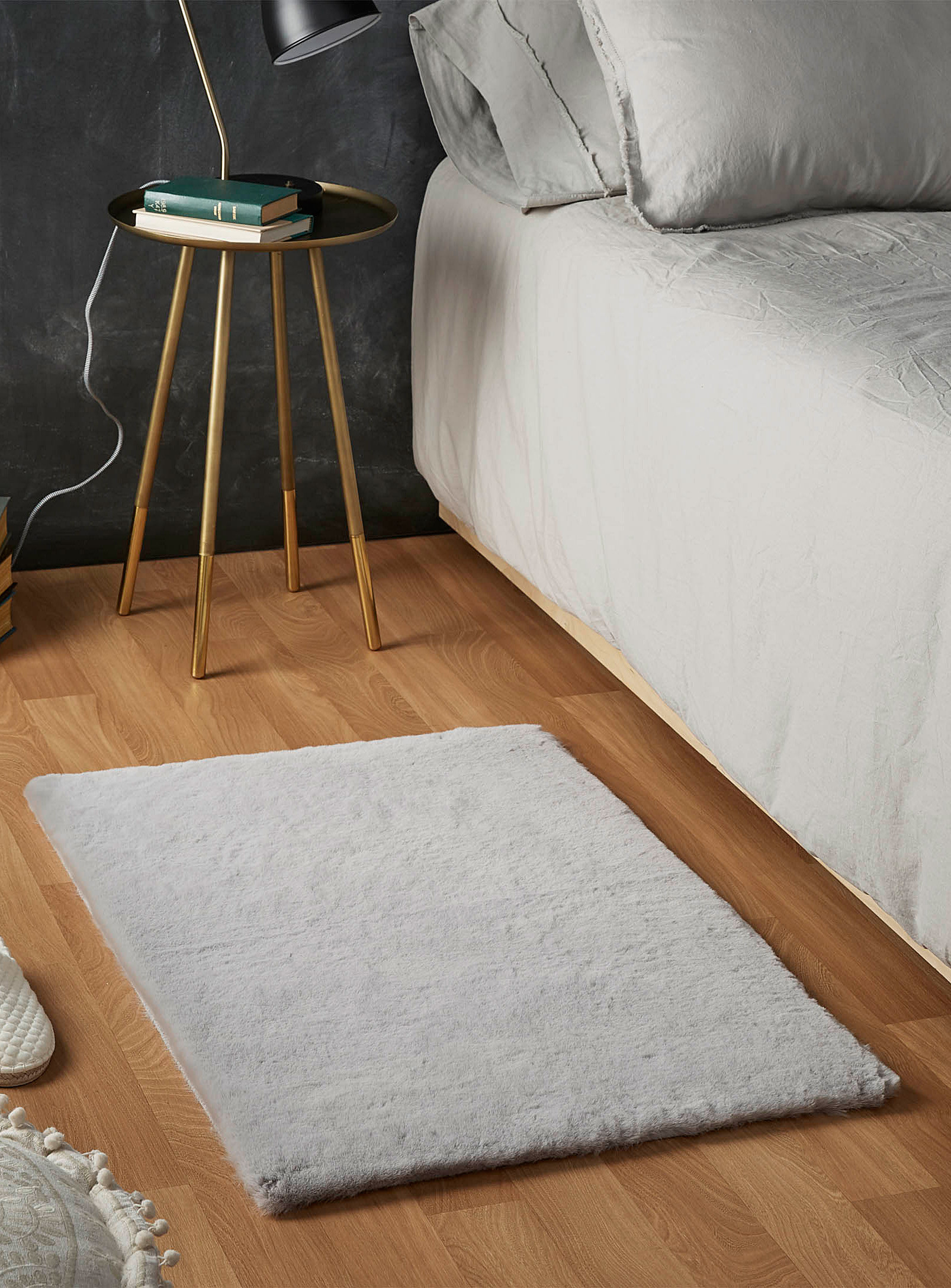 A faux fur rug on the floor near a bed