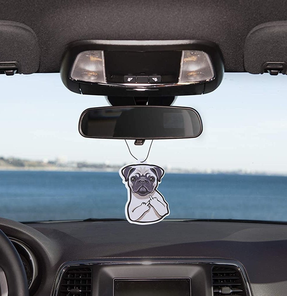 The pug air freshener hanging from a rearview mirror