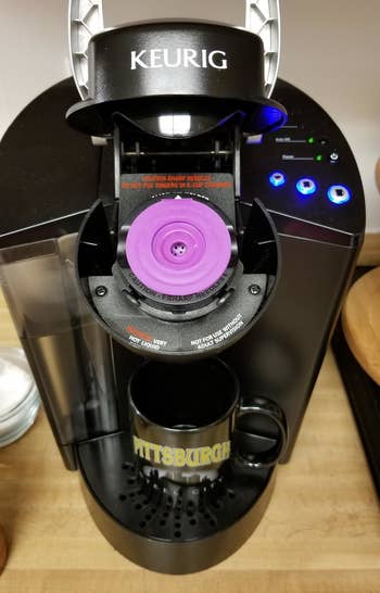 The same purple K-cup closed and inserted into a Keurig 