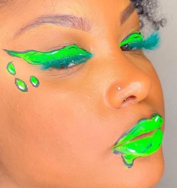 model wearing lime green lipstick and eye makeup with teal faux eyelashes
