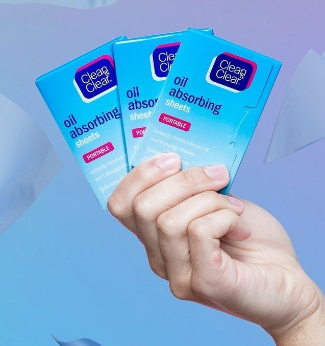 A person holding three packs of blotting papers