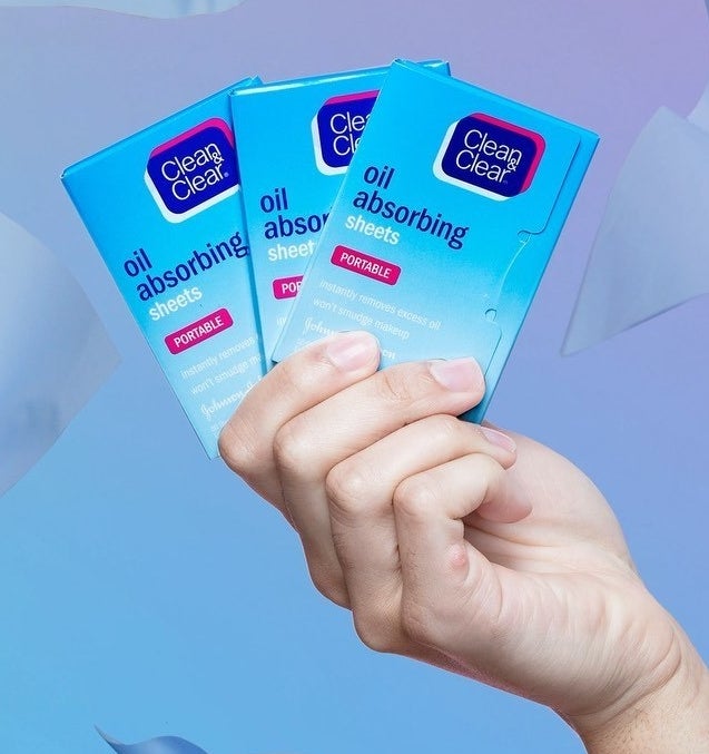 A person holding three packs of blotting papers