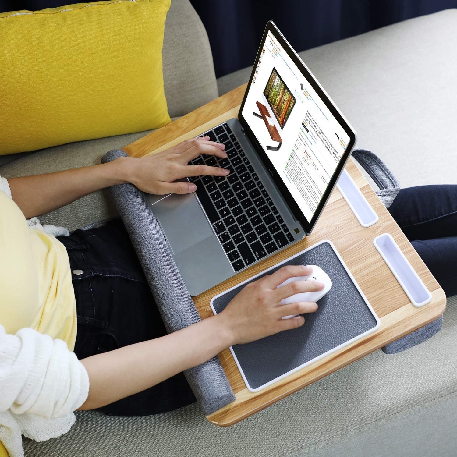 A person using their laptop on the lap desk