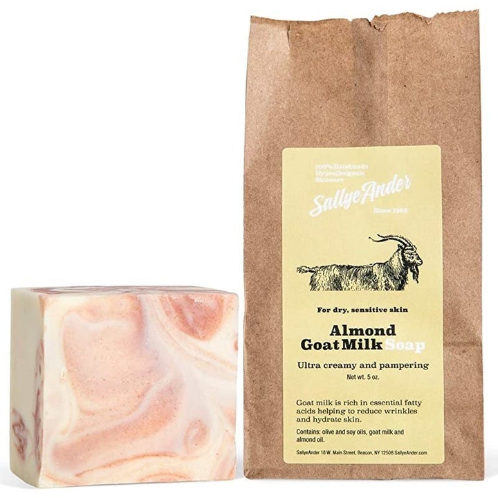 A brown bag with a picture of a goat on it that says "Sally Ander, Almont Goat Milk Soap" sitting next to a pink marbled bar of soap 