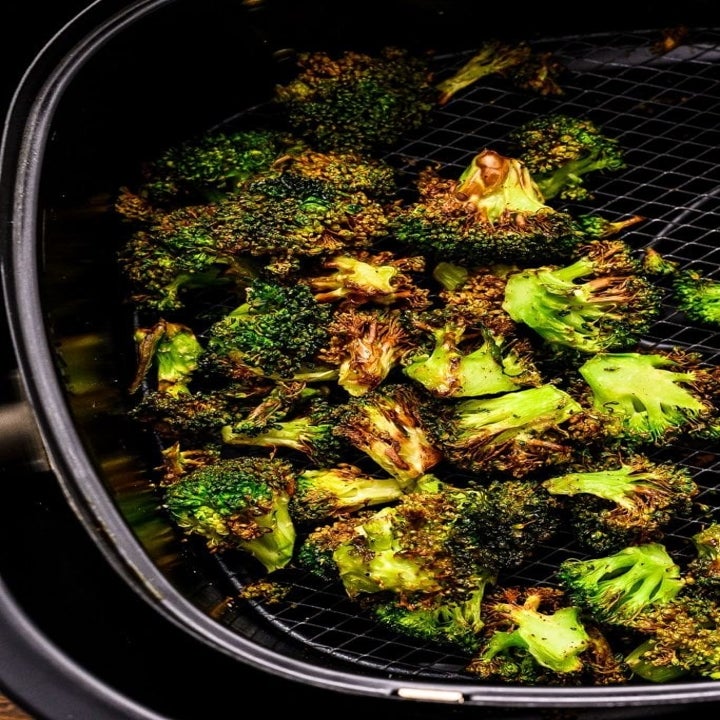 Broccoli florets in the basket of an air fryer.
