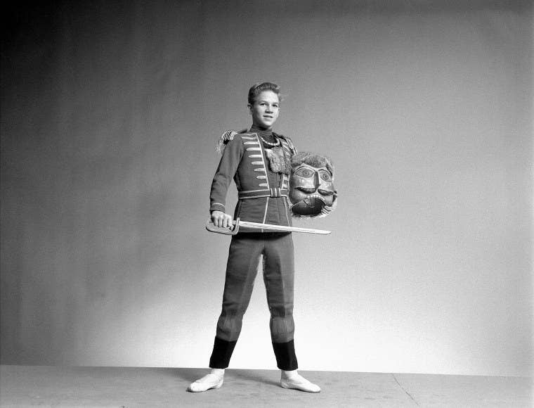 A boy in the Nutcracker costume holds the head and a sword