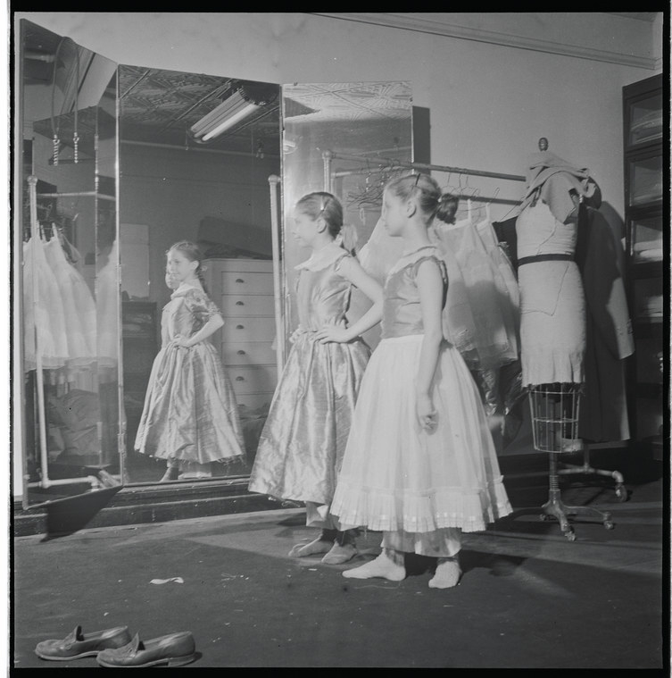 Two girls standing backstage with a.mannequin and mirror