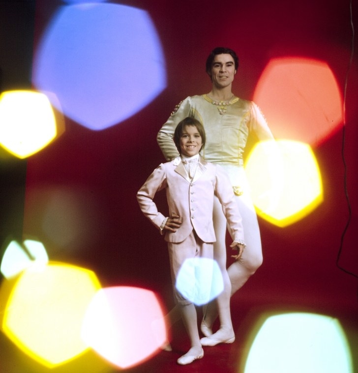 A man and boy make the same pose against a studio backdrop as colorful bokeh lights flash at the camera