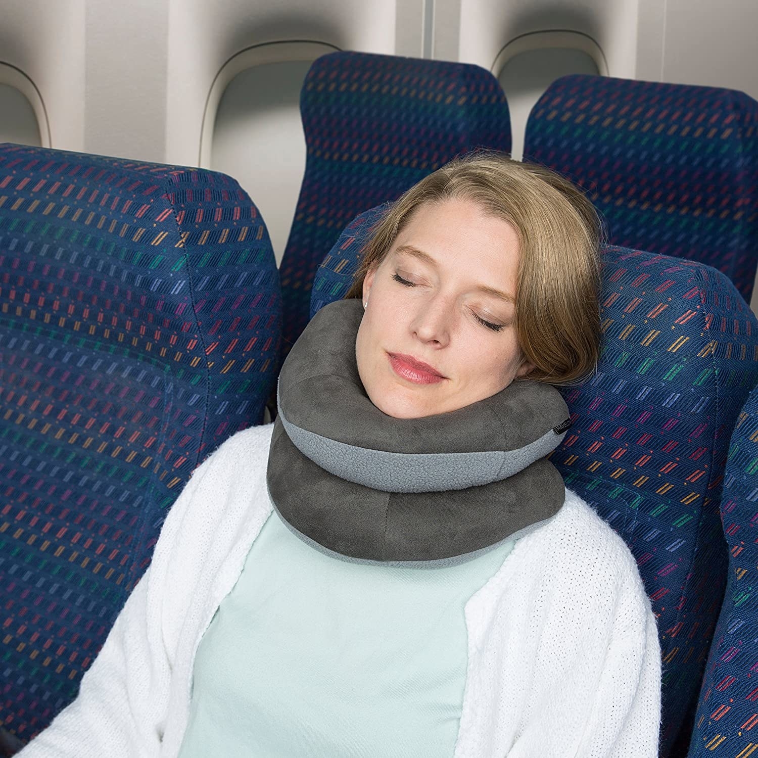 Model using the travel pillow on a plane, wrapping it to give maximum support