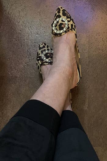 A reviewer wearing the shoes in leopard