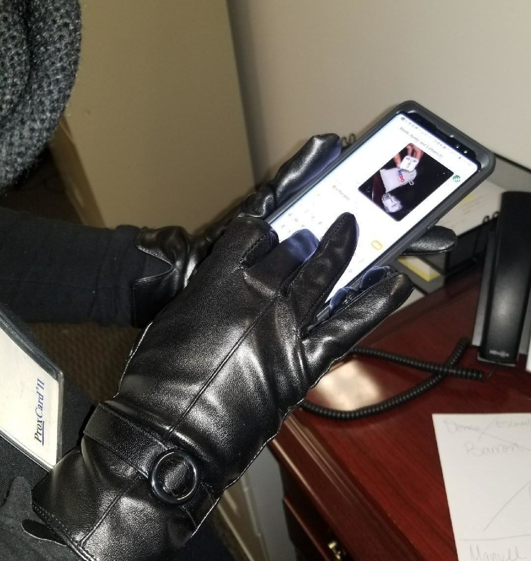 reviewer photo showing person texting while wearing the touchscreen leather gloves in black 