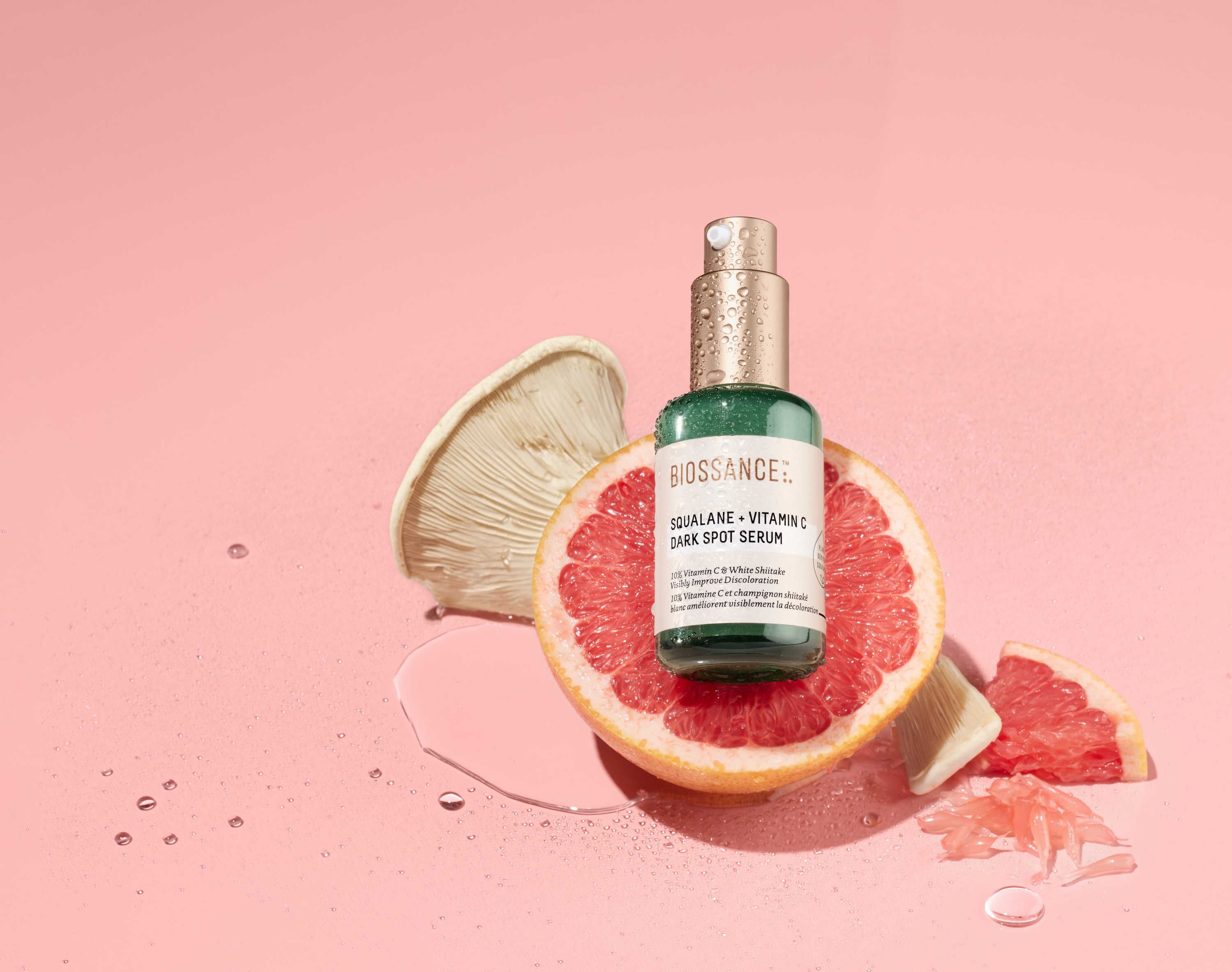 The Squalane and Vitamin C Dark Spot Serum atop a cluster of grapefruit and white mushroom 