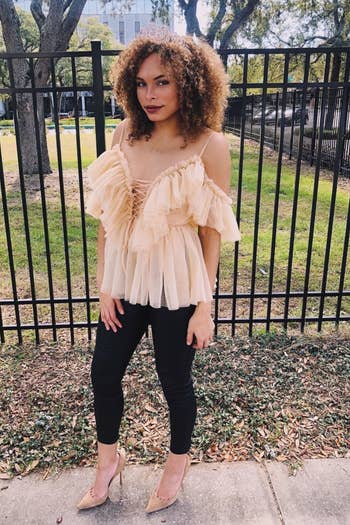 A reviewer wearing the tan cold shoulder tulle ruffle top with short sleeves, spaghetti straps, and a lace-up detail in the front