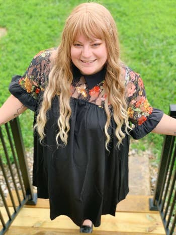 Reviewer wearing the short-sleeved dress with a sheer, colorfully embroidered panel at the shoulders and ruffle-trimmed sleeves in black