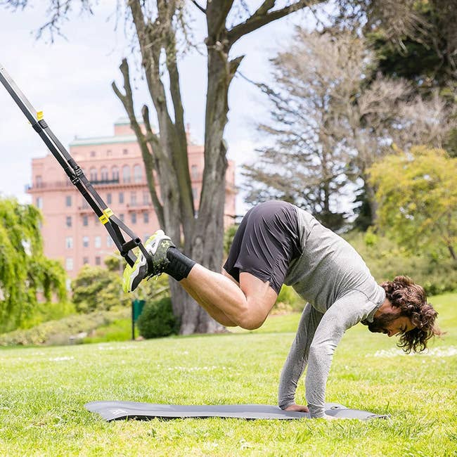Model uses a TRX Suspension Training System to do a full-body move outside
