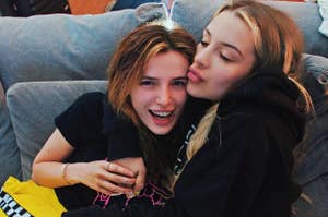 Bella Thorne and Tana Mongeau cuddling on a couch 