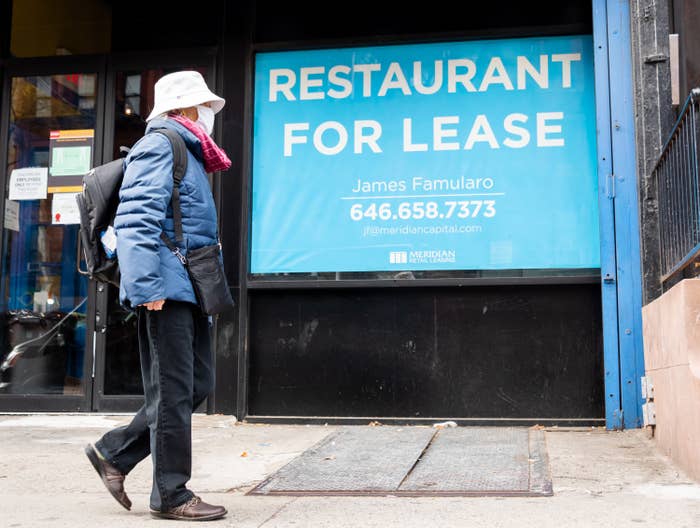 A person walks by a sign that reads &quot;restaurant for lease&quot;