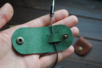 person holding the organizer in green with a headphone wire going through it