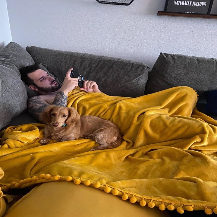 reviewer image of a customer and their dog under the mustard yellow blanket