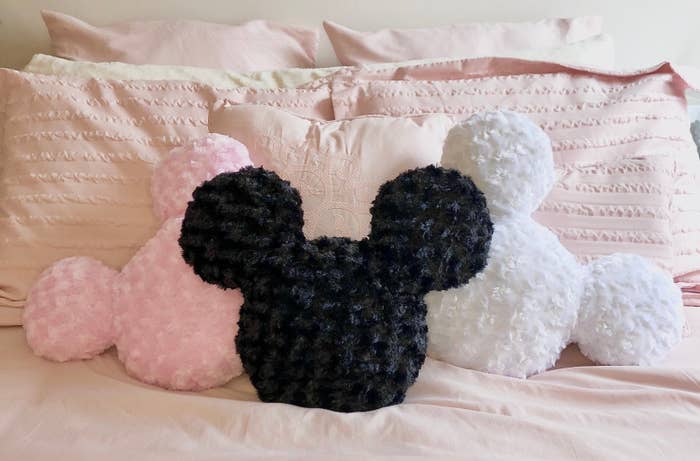 Mickey mouse head shaped pillows on a bed