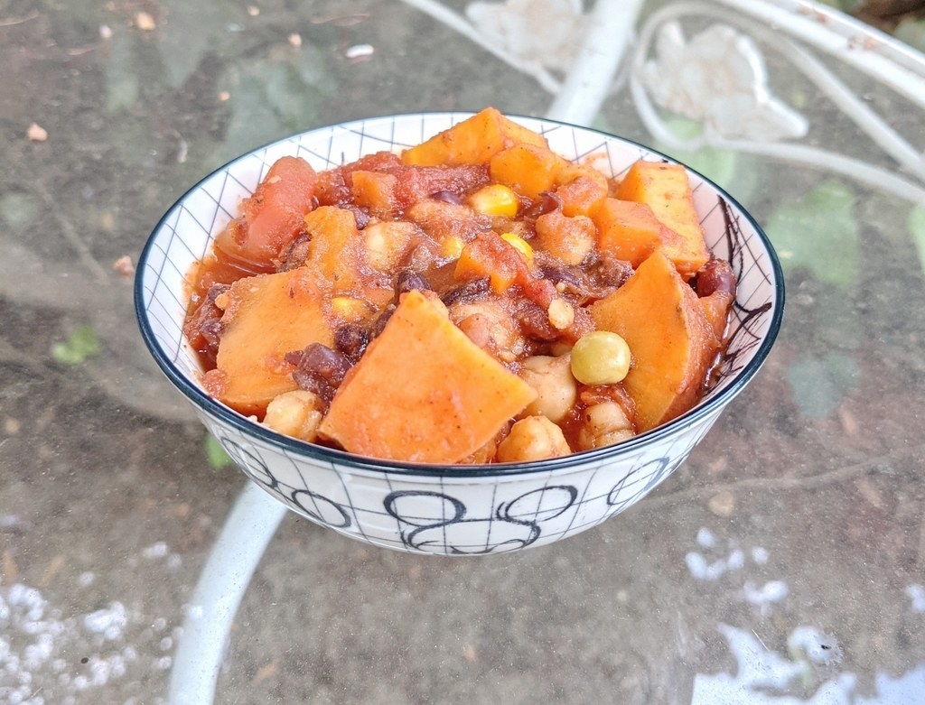 Bowl of chili with sweet potatoes, chickpeas, and tomatoes.