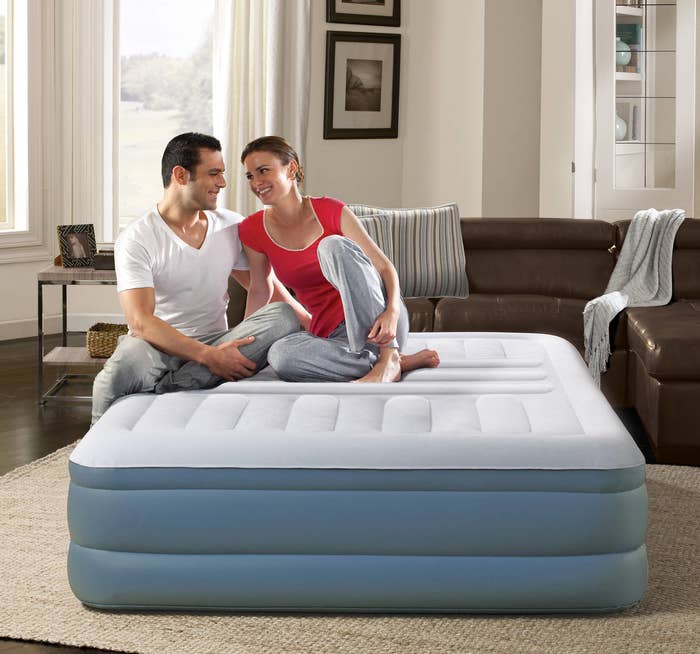 two people sitting on an air mattress in a living room