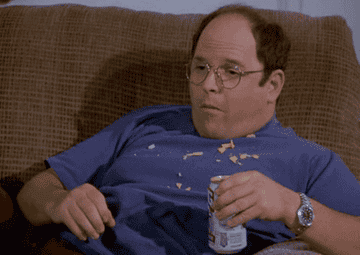 George Costanza eating chips and drinking a beer