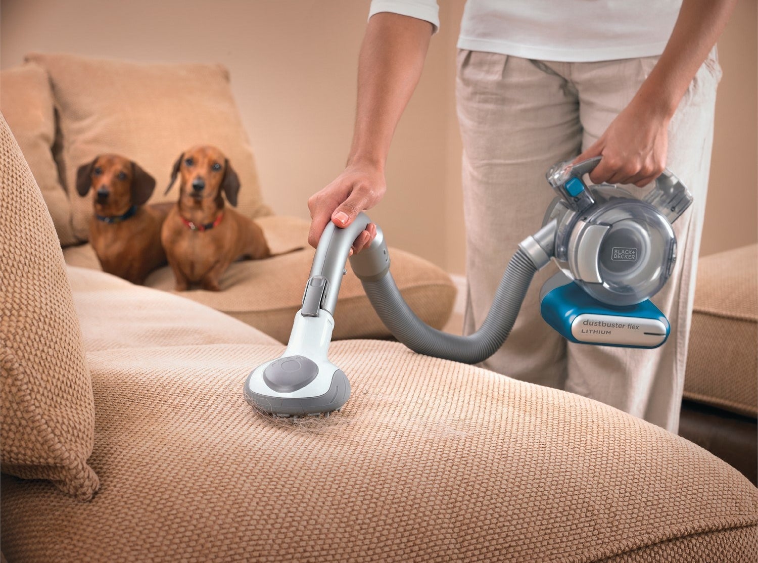 person using a small hand vacuum to suck up pet hair
