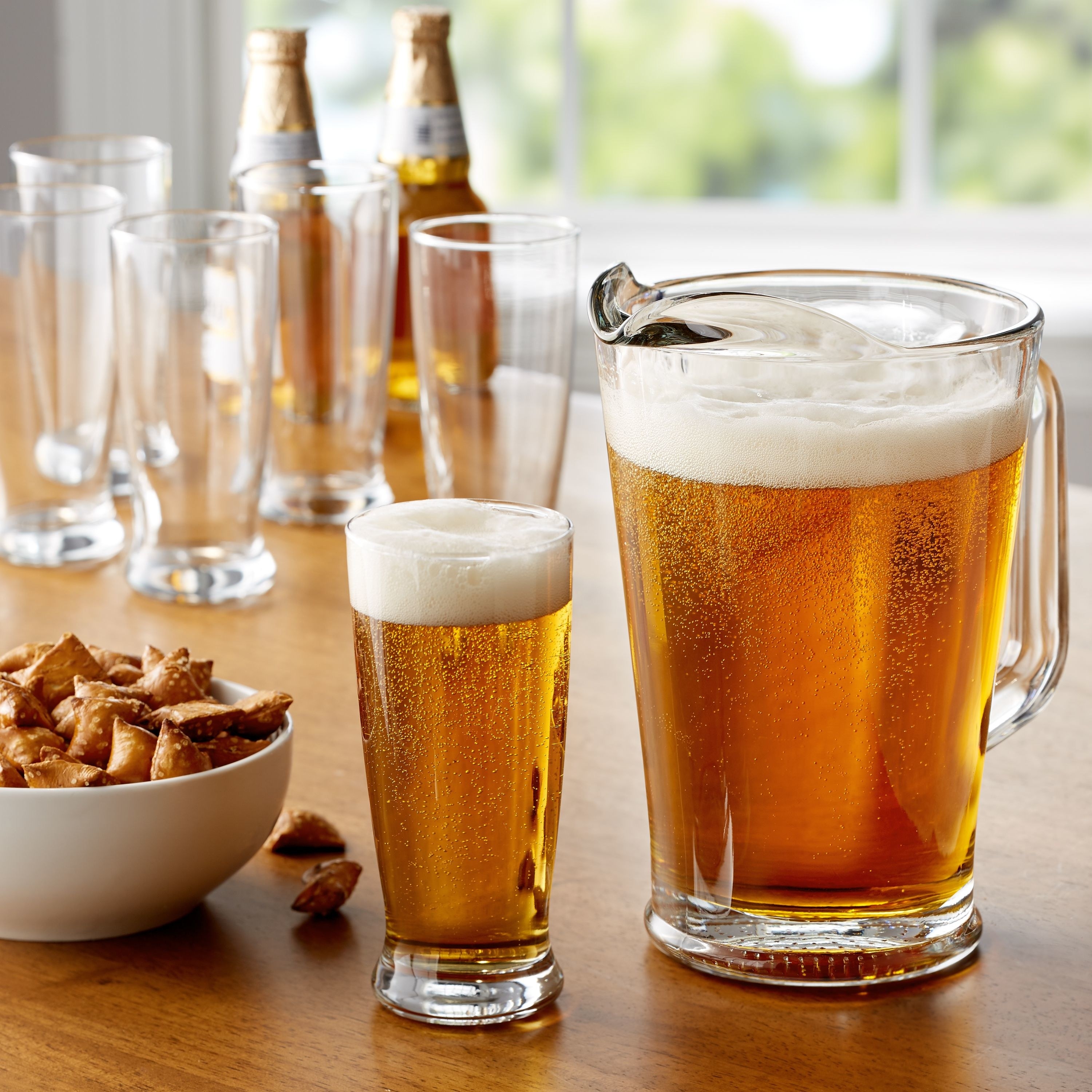 big pitcher and pint glasses with beer in them on a wood table