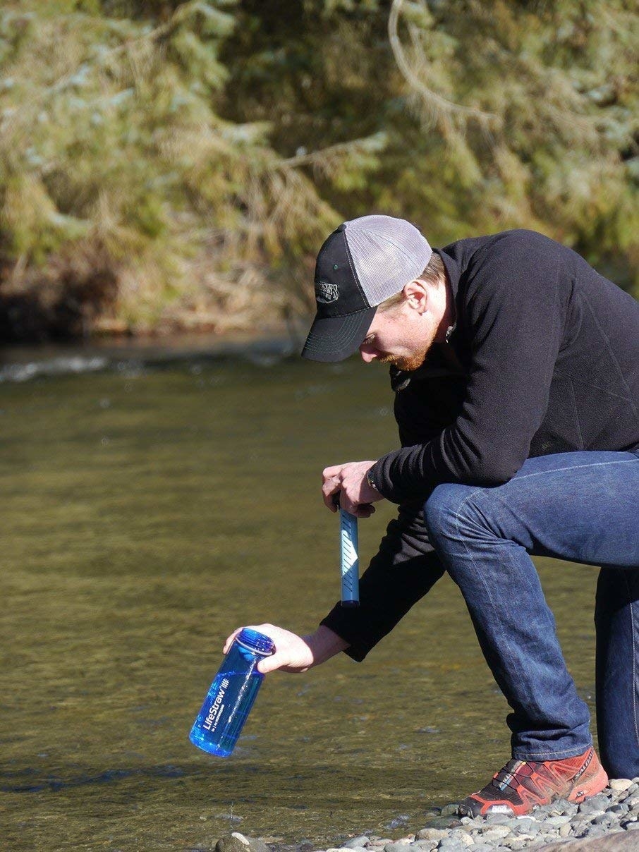 A person filling up the water bottle with river water.