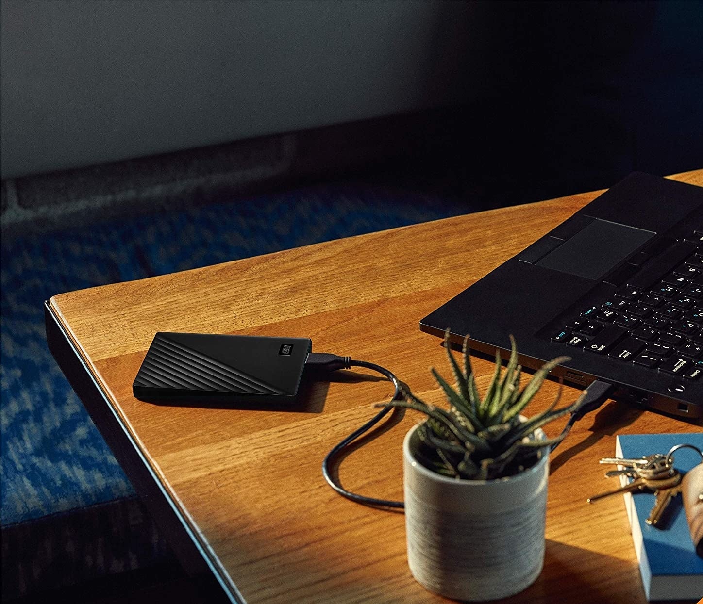 A small rectangular external hard drive lying next to a laptop