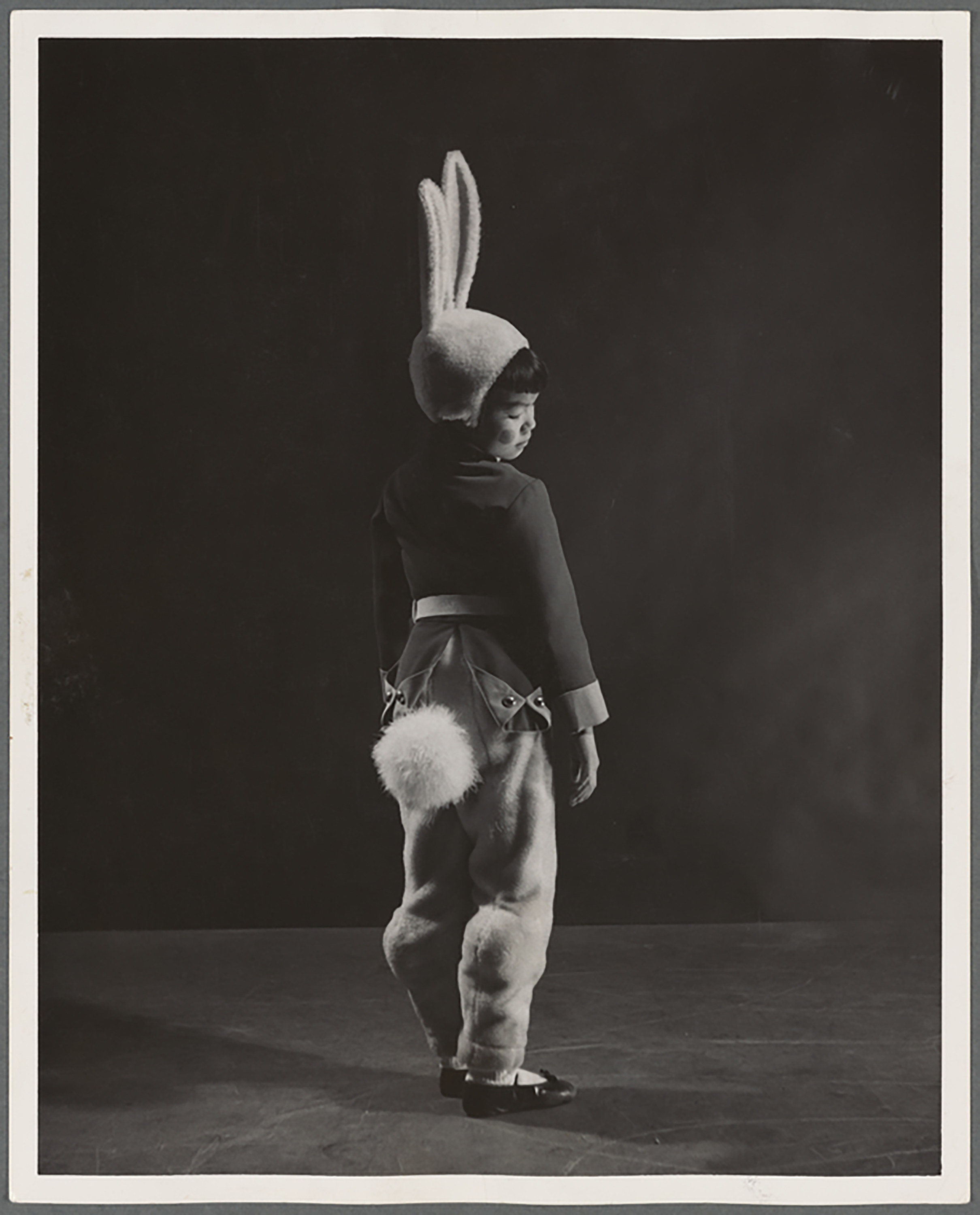 A Black and white image of a small boy in a bunny costume with a fluffy tail