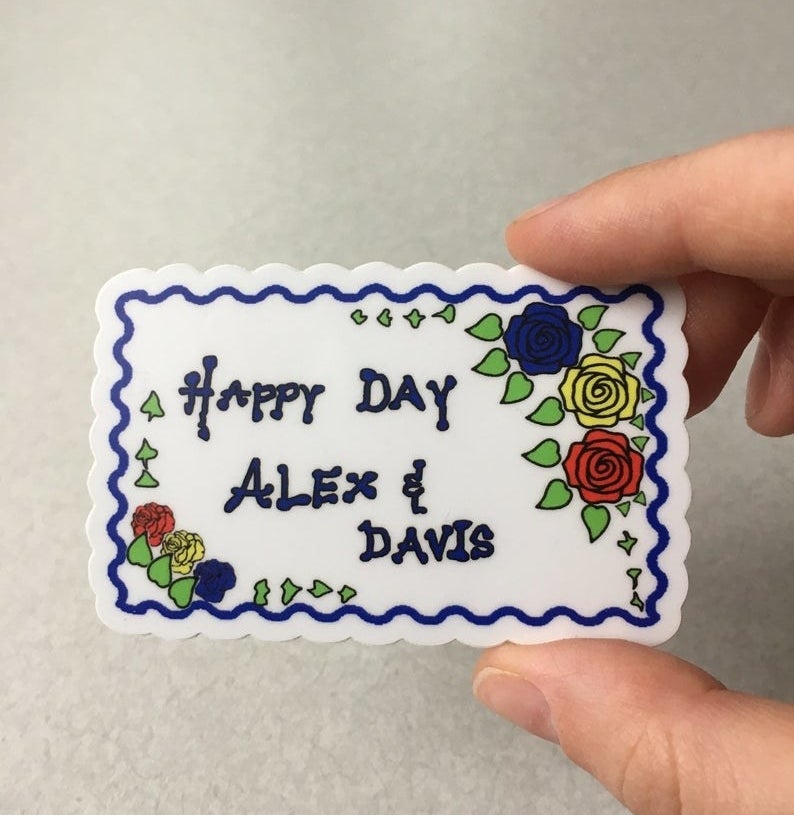 A sticker shaped like the &quot;Happy Day Alex &amp;amp; Davis&quot; cake from the show