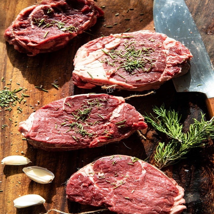 Raw steaks seasoned with rosemary and garlic.