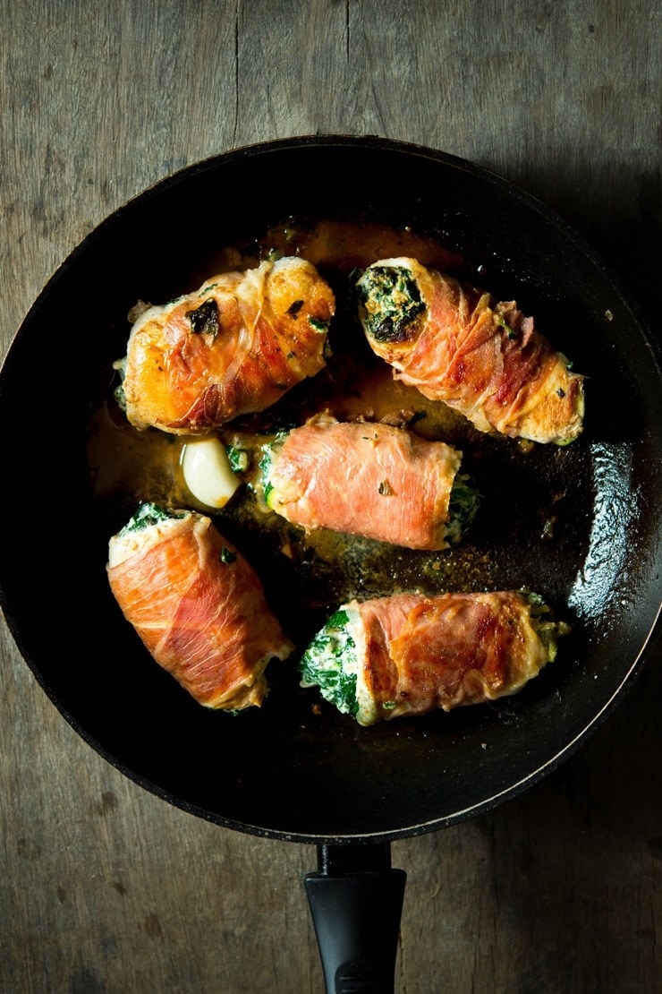 A skillet of five chicken breasts rolled with prosciutto, spinach, and ricotta cheese.