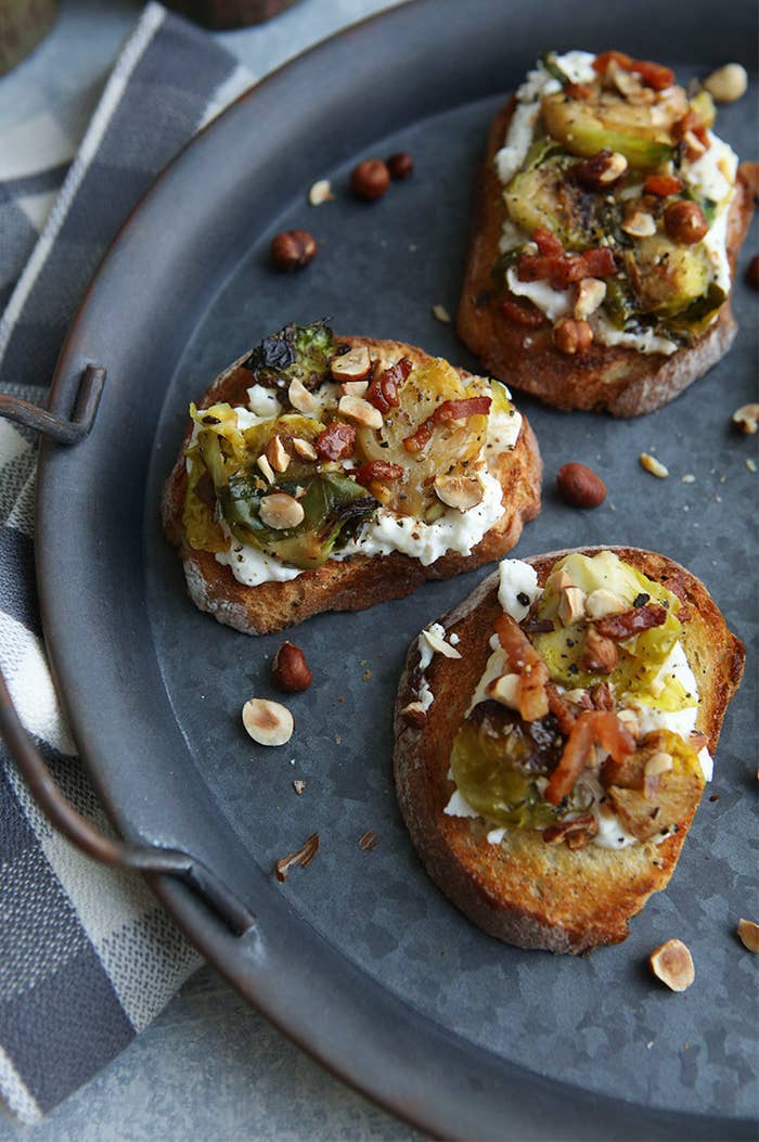 Three bruschetta topped with Brussels sprouts, pancetta, and burrata cheese.