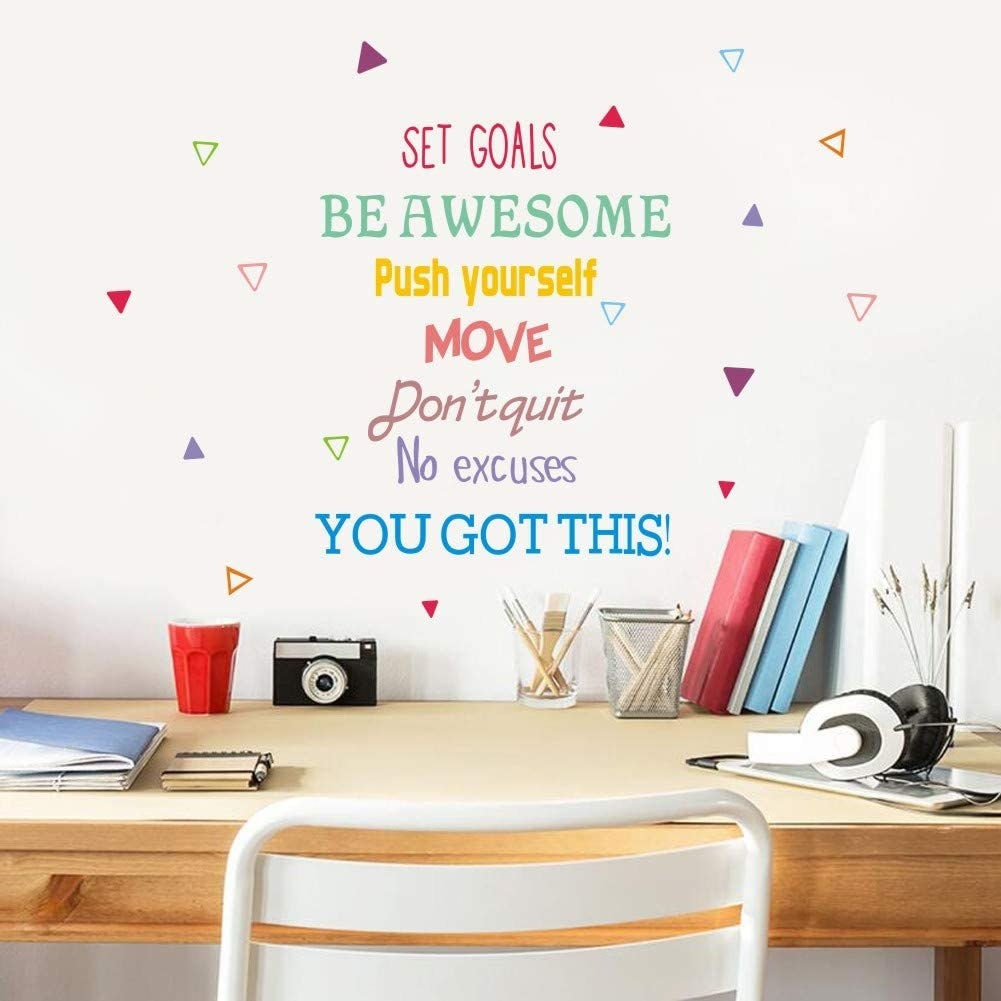 A bunch of motivational decals on the wall above a desk