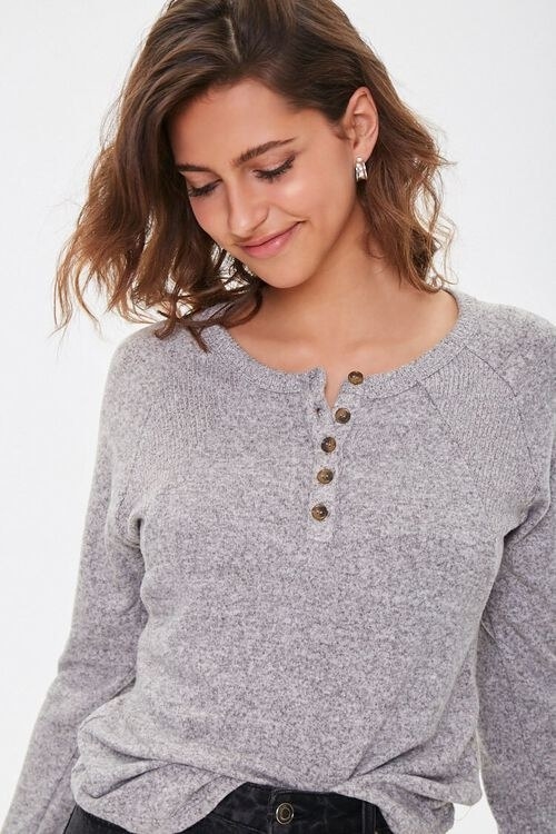 a model in a gray long sleeve with buttons down the middle