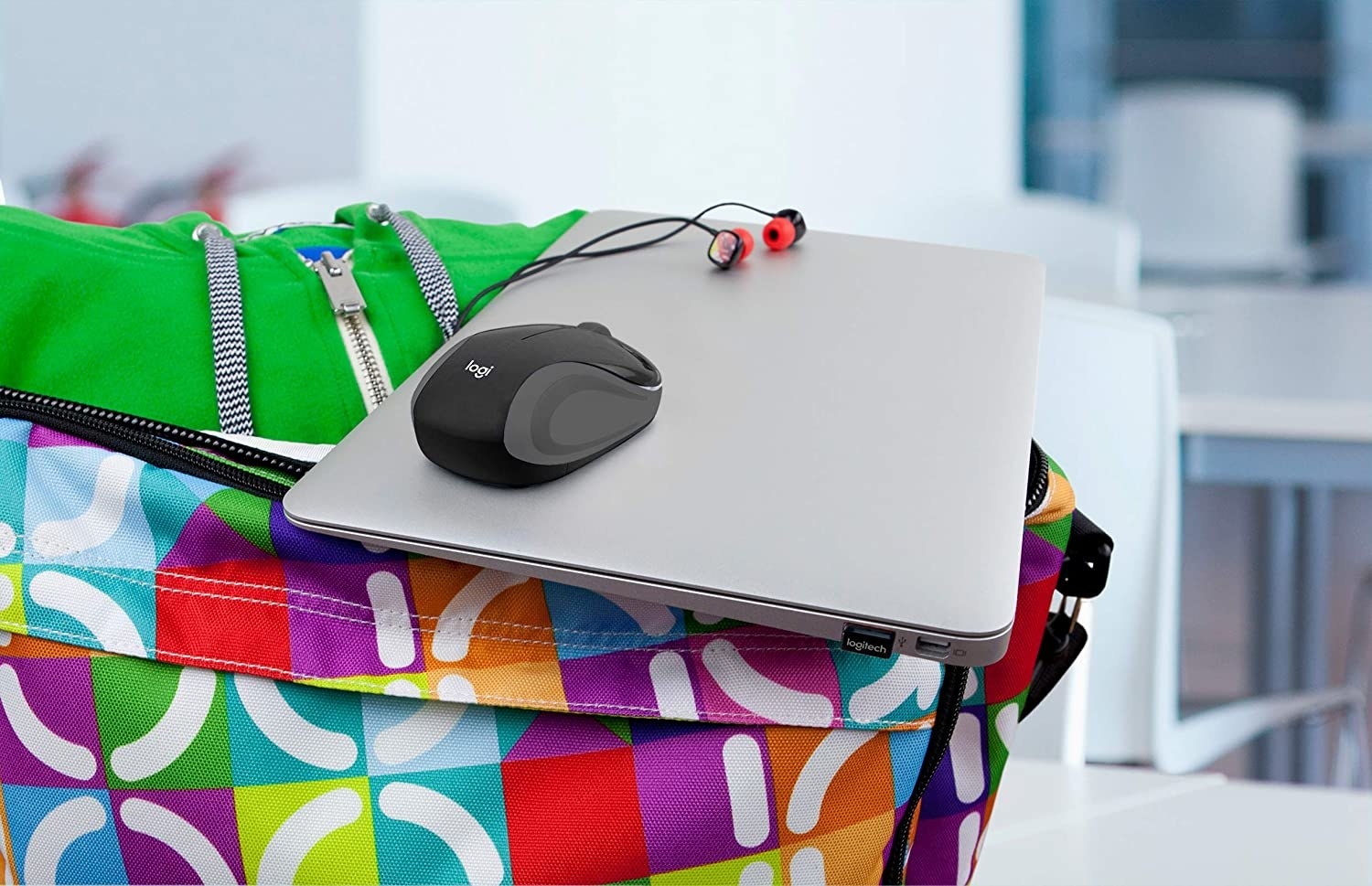 the mouse on a laptop next to some earbuds on a backpack