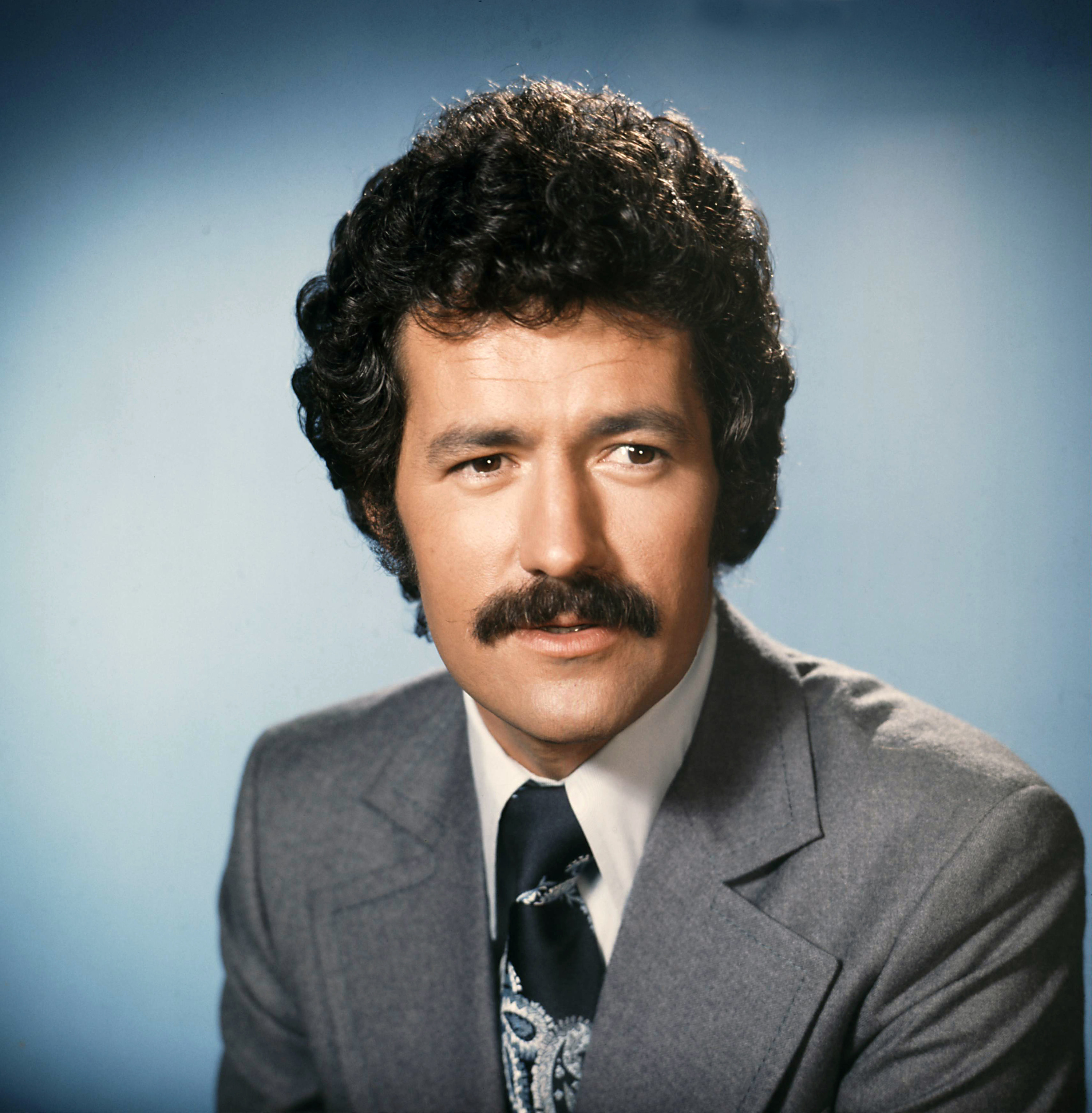 Trebek on blue background looking off to side of the camera 