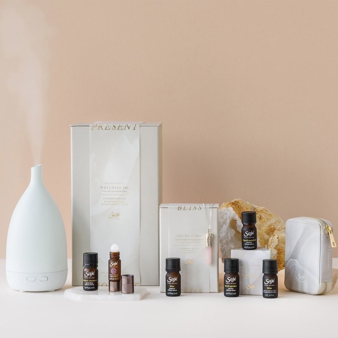 A diffuser next to several bottles of essential oils and rollerballs