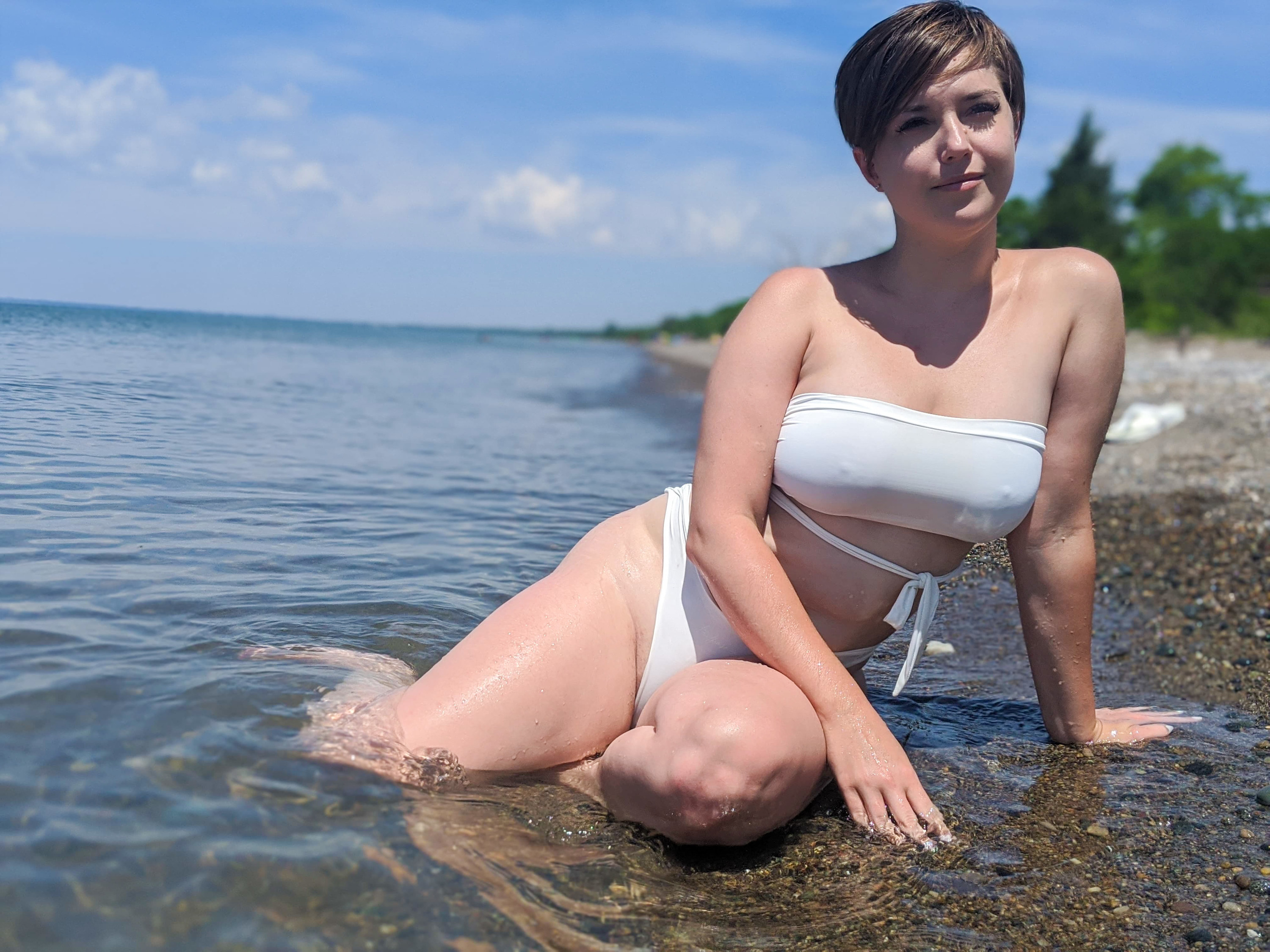 A person wearing a two piece bikini and sitting on a beach