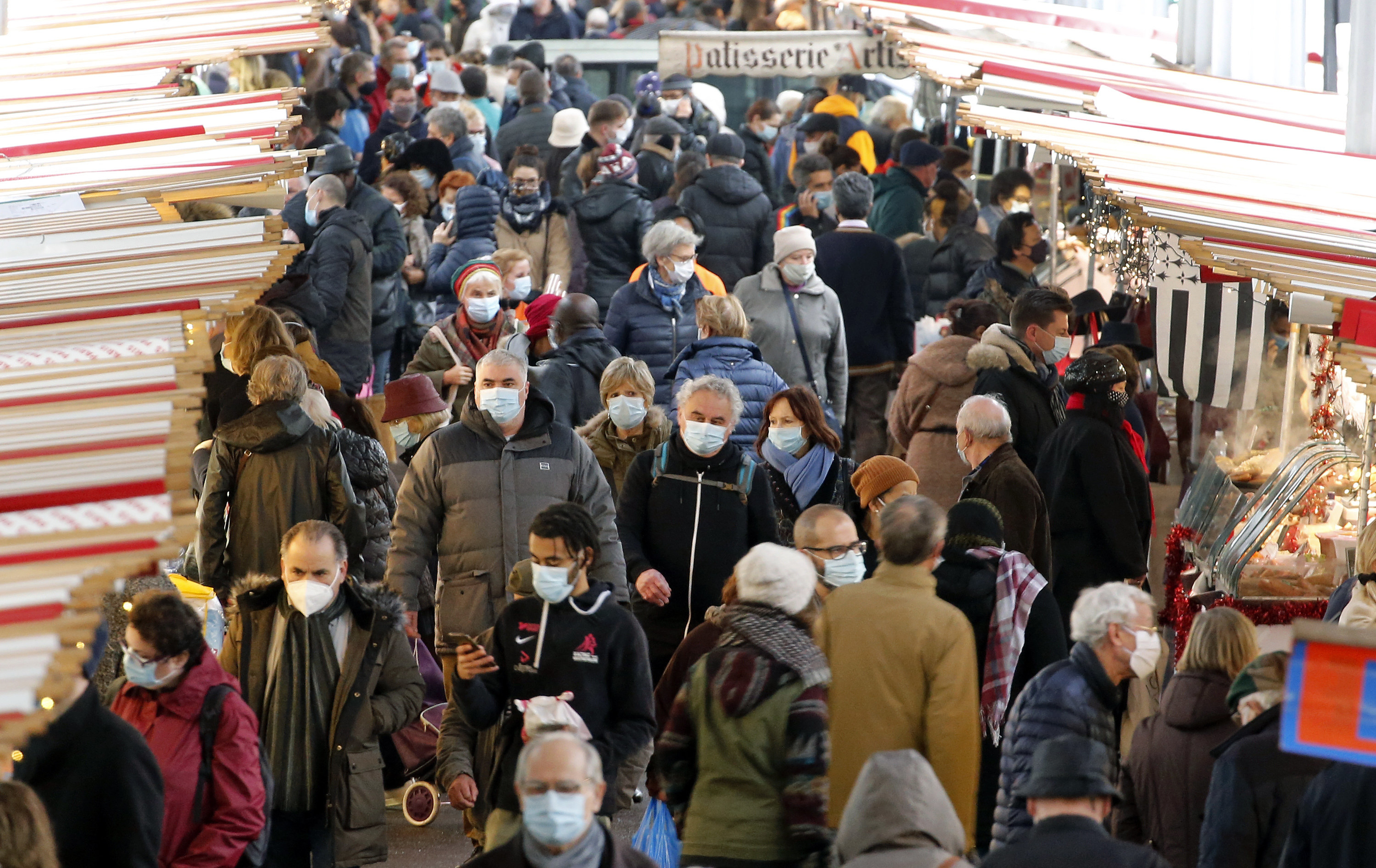 A crowd of people walk with face masks on