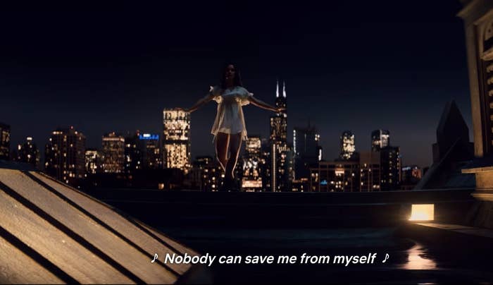 Cassie Shore dancing on the ledge in a white dress; chicago skyline in the background. &quot;Nobody can save me from myself&quot; lyric.