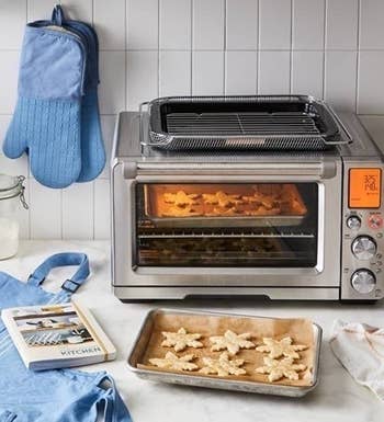 the toaster oven on a counter near a tray of cookies
