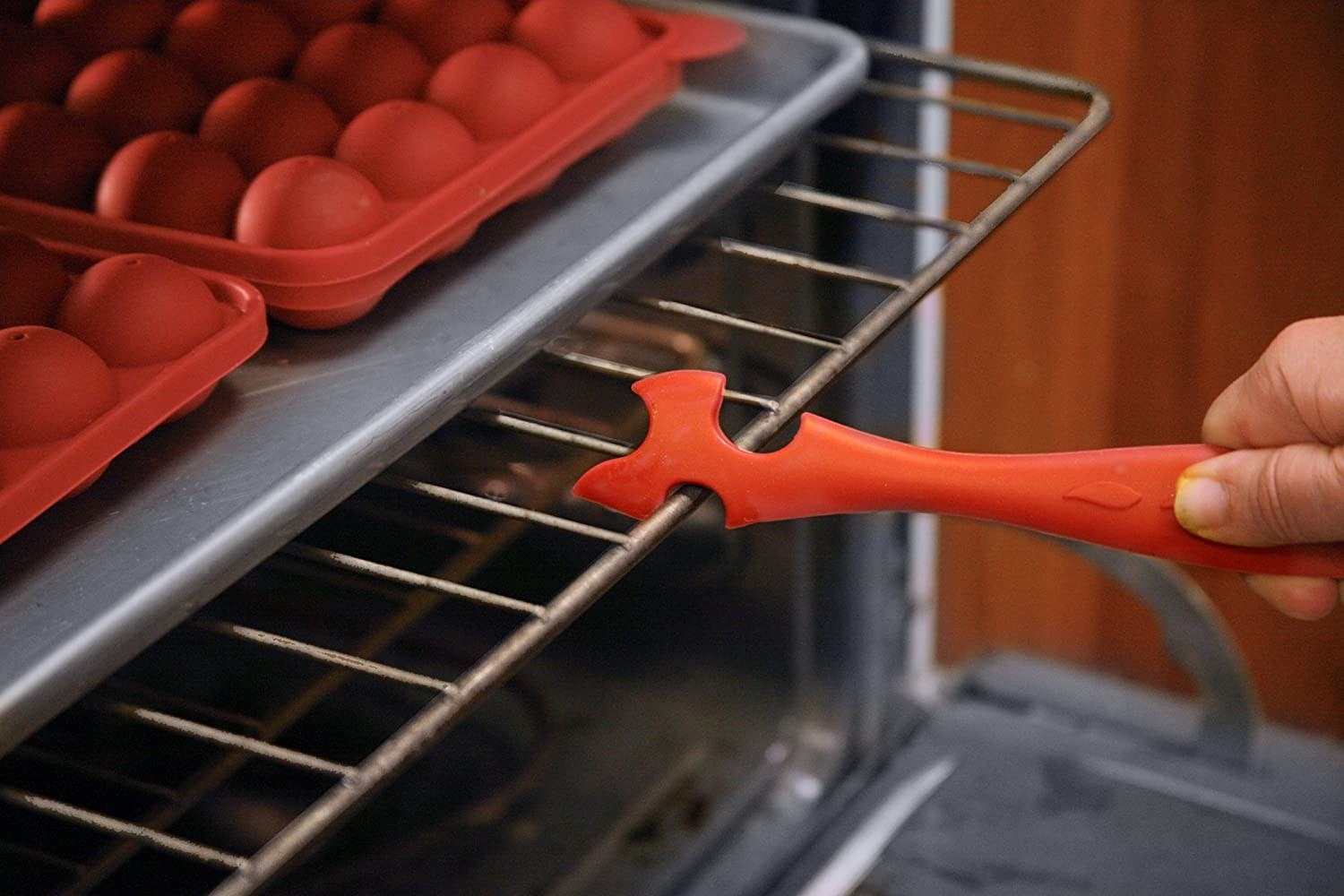 A person pulling out an oven rack with the tool